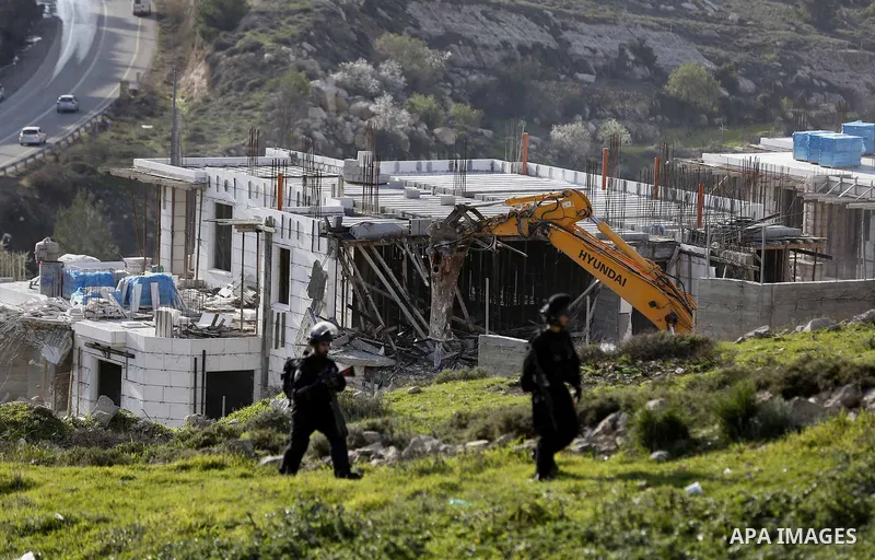 Israeli border police officers stand guard as Israeli machineries demolish an under-construction Palestinian residential building near Hebron, in the occupied West Bank February 14, 2018. Photo by Wisam Hashlamoun