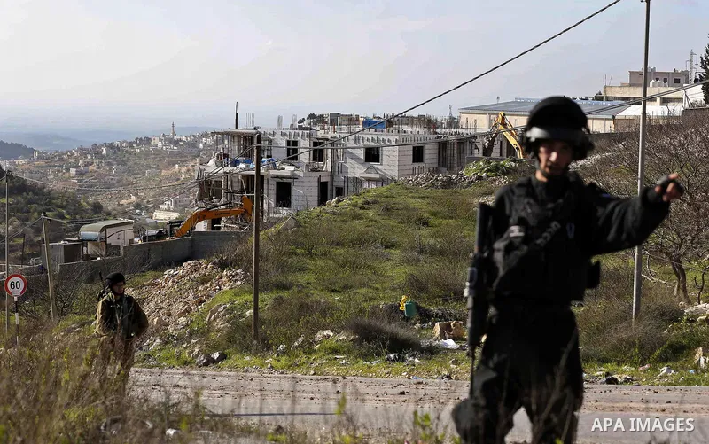 Israeli border police officers stand guard as Israeli machineries demolish an under-construction Palestinian residential building near Hebron, in the occupied West Bank February 14, 2018. Photo by Wisam Hashlamoun