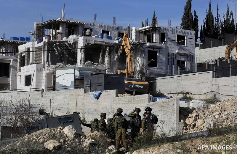 Israeli border police officers stand guard as Israeli machineries demolish an under-construction Palestinian residential building near Hebron, in the occupied West Bank February 14, 2018. Photo by Wisam Hashlamoun