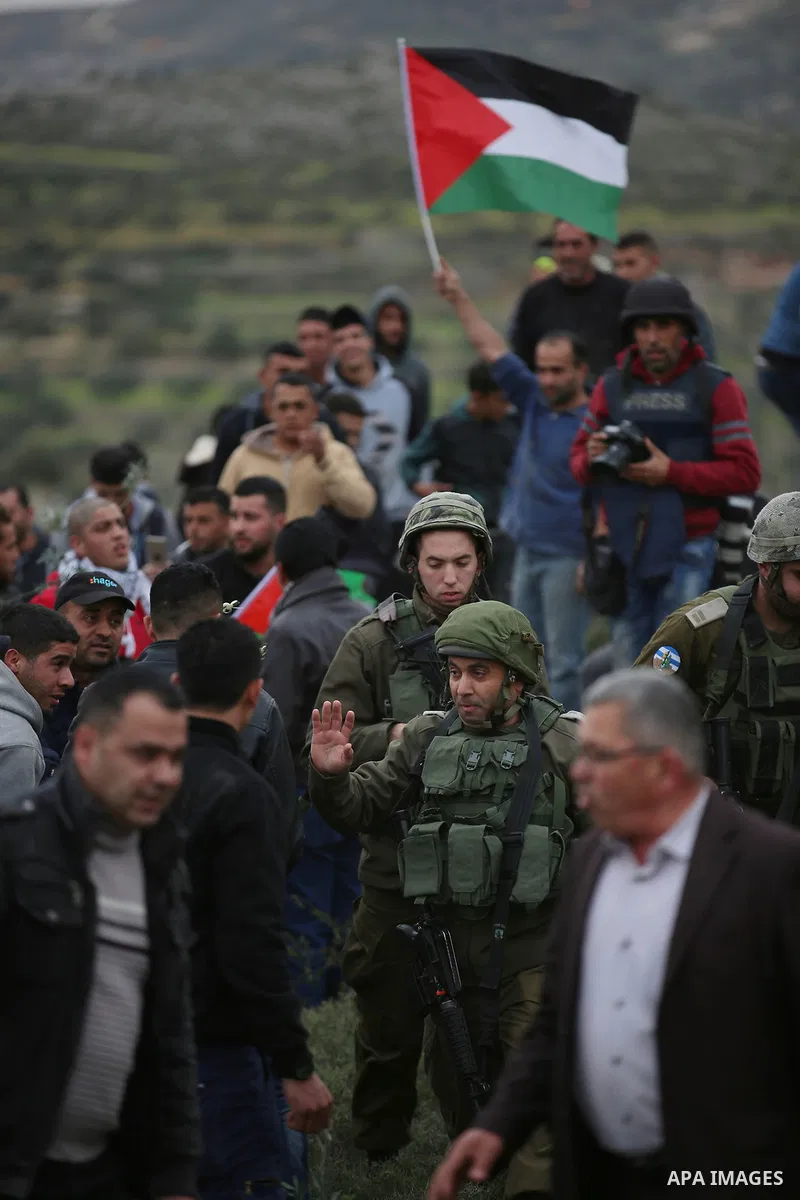 Palestinians try to plant olive trees as Israeli troops stand guard during a protest against Jewish settlements in the village of Beita, near Nablus in the occupied West Bank February 15, 2018. Photo by Shadi Jarar'ah
