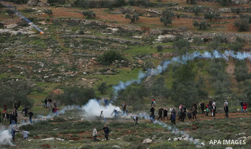 Palestinian protesters stand in a cloud of tear gas fired by Israeli troops during clashes at the Beta village near the West Bank city of Nablus, 15 February 2018. According to local sources at least five Palestinian wer...