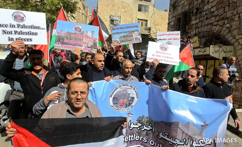 Palestinian protesters take part in a demonstration demanding to dismantle the Ghetto, to mark the 24th anniversary of Ibrahimi mosque massacre when Baruch Goldstein an Israeli settler opened fire and killing 29 Palestin...