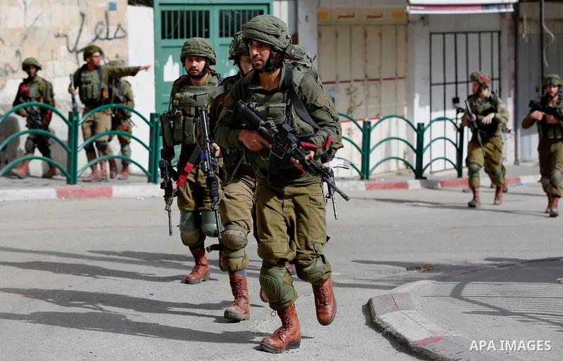 Israeli soldiers take position during clashes with Palestinian protesters following a demonstration demanding to dismantle the Ghetto, to mark the 24th anniversary of Ibrahimi mosque massacre when Baruch Goldstein an Isr...