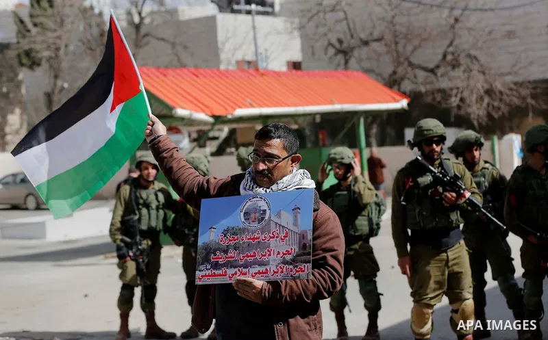 Palestinian protesters take part in a demonstration demanding to dismantle the Ghetto, to mark the 24th anniversary of Ibrahimi mosque massacre when Baruch Goldstein an Israeli settler opened fire and killing 29 Palestin...