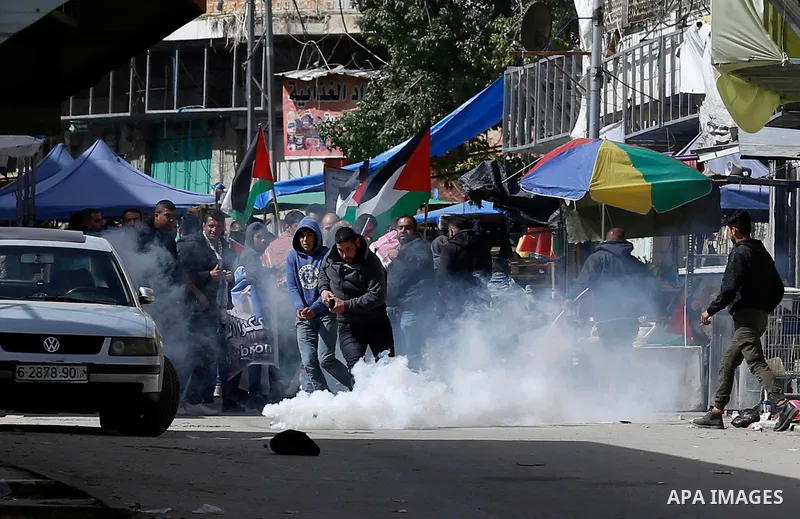 Palestinian protesters run for cover from tear gas is fired by Israeli troops during clashes following a demonstration demanding to dismantle the Ghetto, to mark the 24th anniversary of Ibrahimi mosque massacre when Baru...