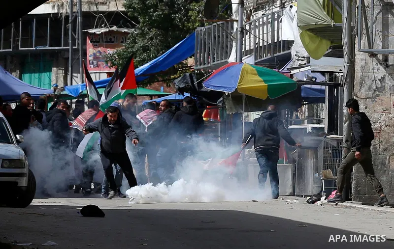 Palestinian protesters run for cover from tear gas is fired by Israeli troops during clashes following a demonstration demanding to dismantle the Ghetto, to mark the 24th anniversary of Ibrahimi mosque massacre when Baru...