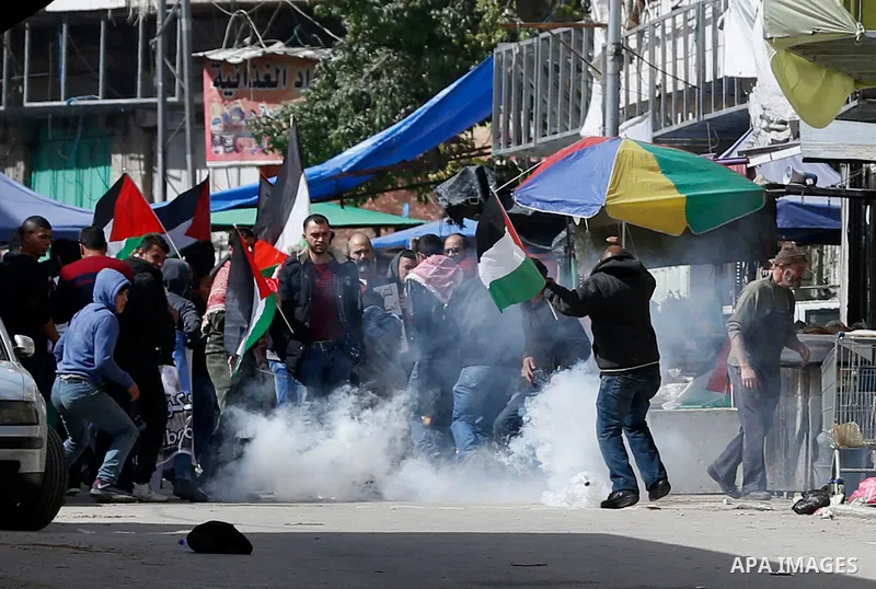 Palestinian protesters run for cover from tear gas is fired by Israeli troops during clashes following a demonstration demanding to dismantle the Ghetto, to mark the 24th anniversary of Ibrahimi mosque massacre when Baru...