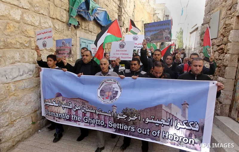 Palestinian protesters take part in a demonstration demanding to dismantle the Ghetto, to mark the 24th anniversary of Ibrahimi mosque massacre when Baruch Goldstein an Israeli settler opened fire and killing 29 Palestin...