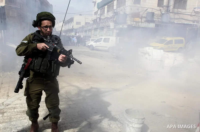 Israeli soldiers take position during clashes with Palestinian protesters following a demonstration demanding to dismantle the Ghetto, to mark the 24th anniversary of Ibrahimi mosque massacre when Baruch Goldstein an Isr...