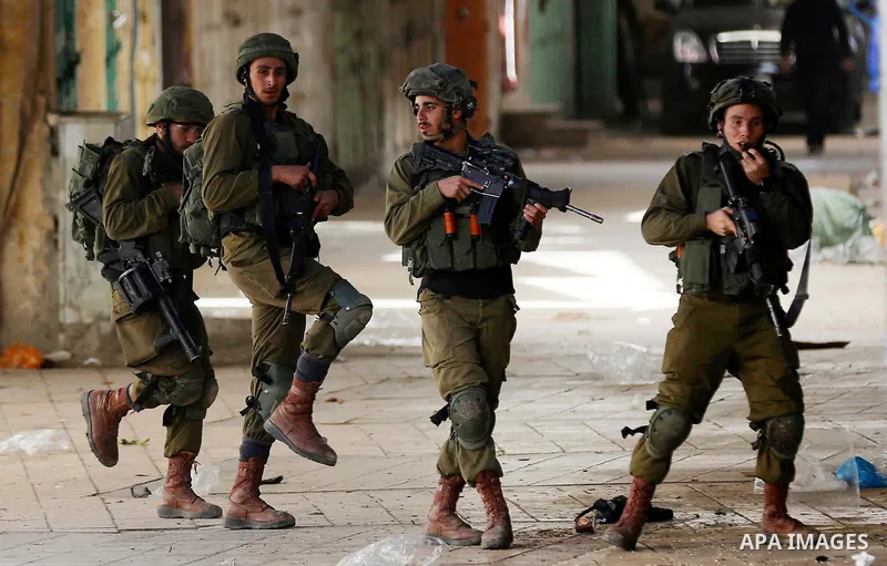 Israeli soldiers take position during clashes with Palestinian protesters following a demonstration demanding to dismantle the Ghetto, to mark the 24th anniversary of Ibrahimi mosque massacre when Baruch Goldstein an Isr...