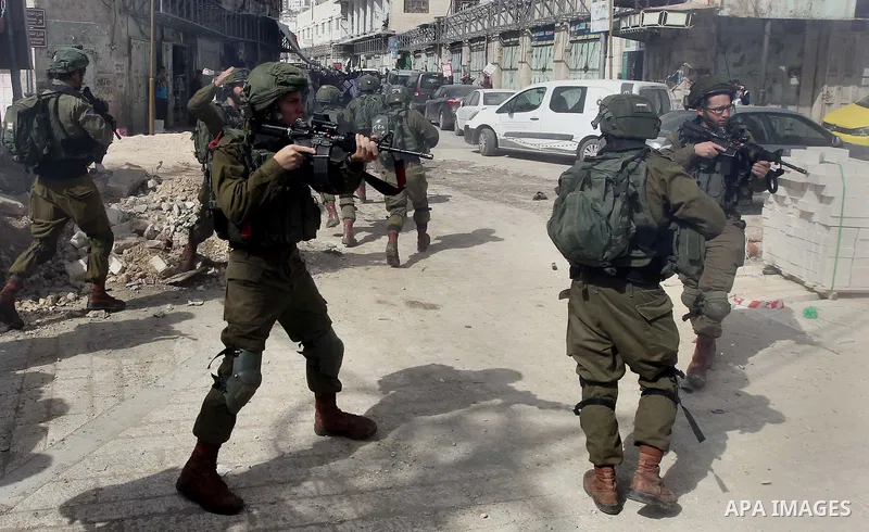 Israeli soldiers take position during clashes with Palestinian protesters following a demonstration demanding to dismantle the Ghetto, to mark the 24th anniversary of Ibrahimi mosque massacre when Baruch Goldstein an Isr...