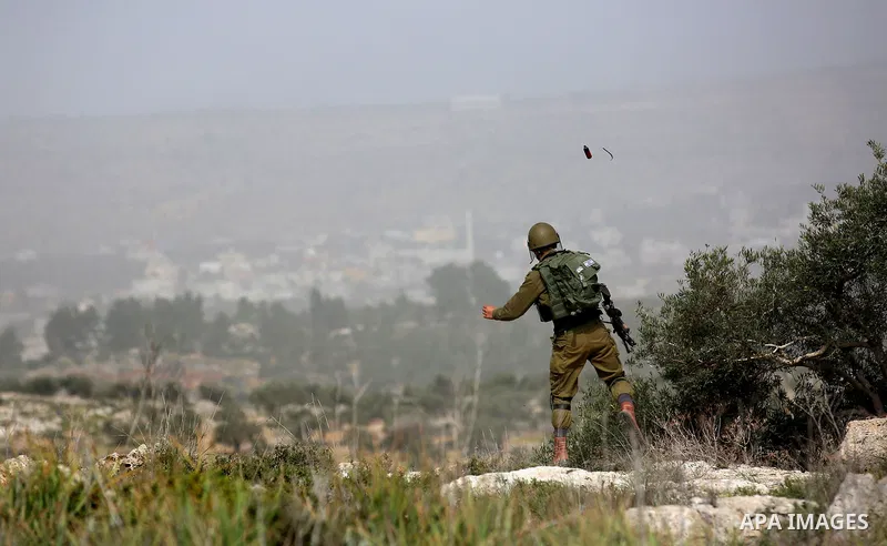 A member of Israeli security forces throws a tear gas canister towards Palestinian protesters during clashes in the occupied West Bank village of Baita, outside of Nablus, on February 16, 2018. Photo by Shadi Jarar'ah