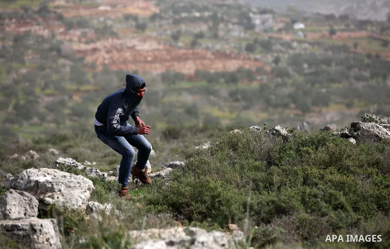 A Palestinian protester hurls stones towards Israeli security forces during clashes in the occupied West Bank village of Baita, just outside of Nablus, on February 16, 2018. Photo by Shadi Jarar'ah