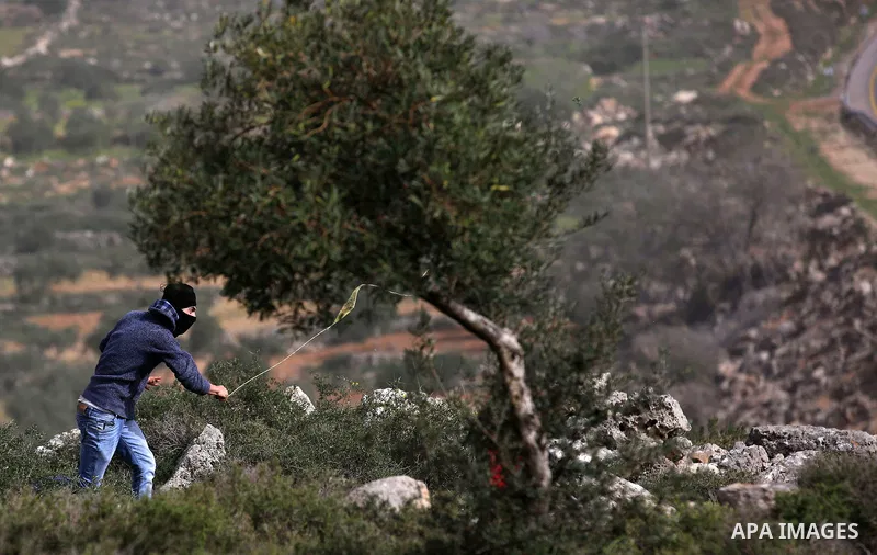 A Palestinian protester uses a slingshot to hurl stones towards Israeli security forces during clashes in the occupied West Bank village of Baita, just outside of Nablus, on February 16, 2018. Photo by Shadi Jarar'ah