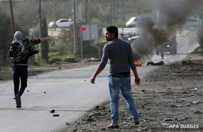 A Palestinian protester uses a slingshot to hurl stones towards Israeli security forces during clashes in the occupied West Bank village of Baita, just outside of Nablus, on February 16, 2018. Photo by Shadi Jarar'ah