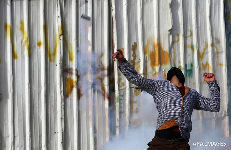 A Palestinian protester throws back a tear gas canister fired by Israeli security forces during clashes in the occupied West Bank village of Baita, just outside of Nablus, on February 16, 2018. Photo by Shadi Jarar'ah