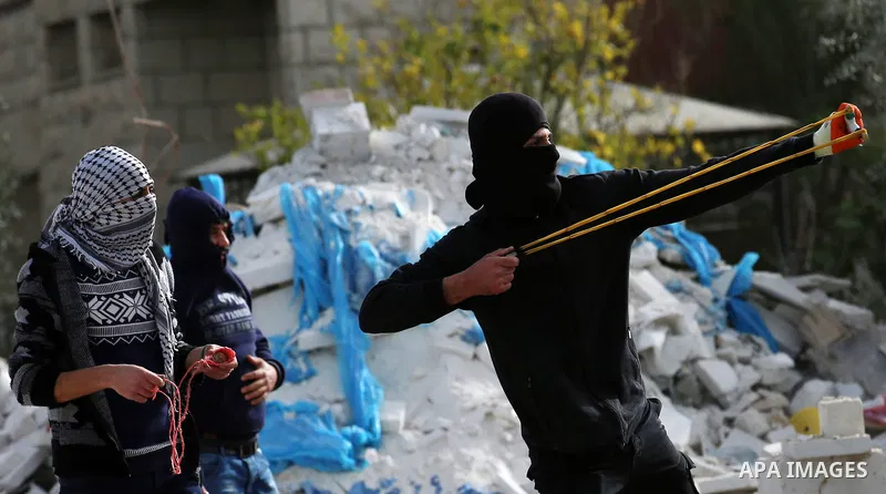 A Palestinian protester uses a slingshot to hurl stones towards Israeli security forces during clashes in the occupied West Bank village of Baita, just outside of Nablus, on February 16, 2018. Photo by Shadi Jarar'ah
