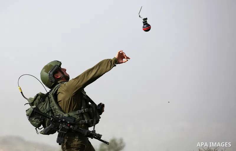 A member of Israeli security forces throws a tear gas canister towards Palestinian protesters during clashes in the occupied West Bank village of Baita, outside of Nablus, on February 16, 2018. Photo by Shadi Jarar'ah