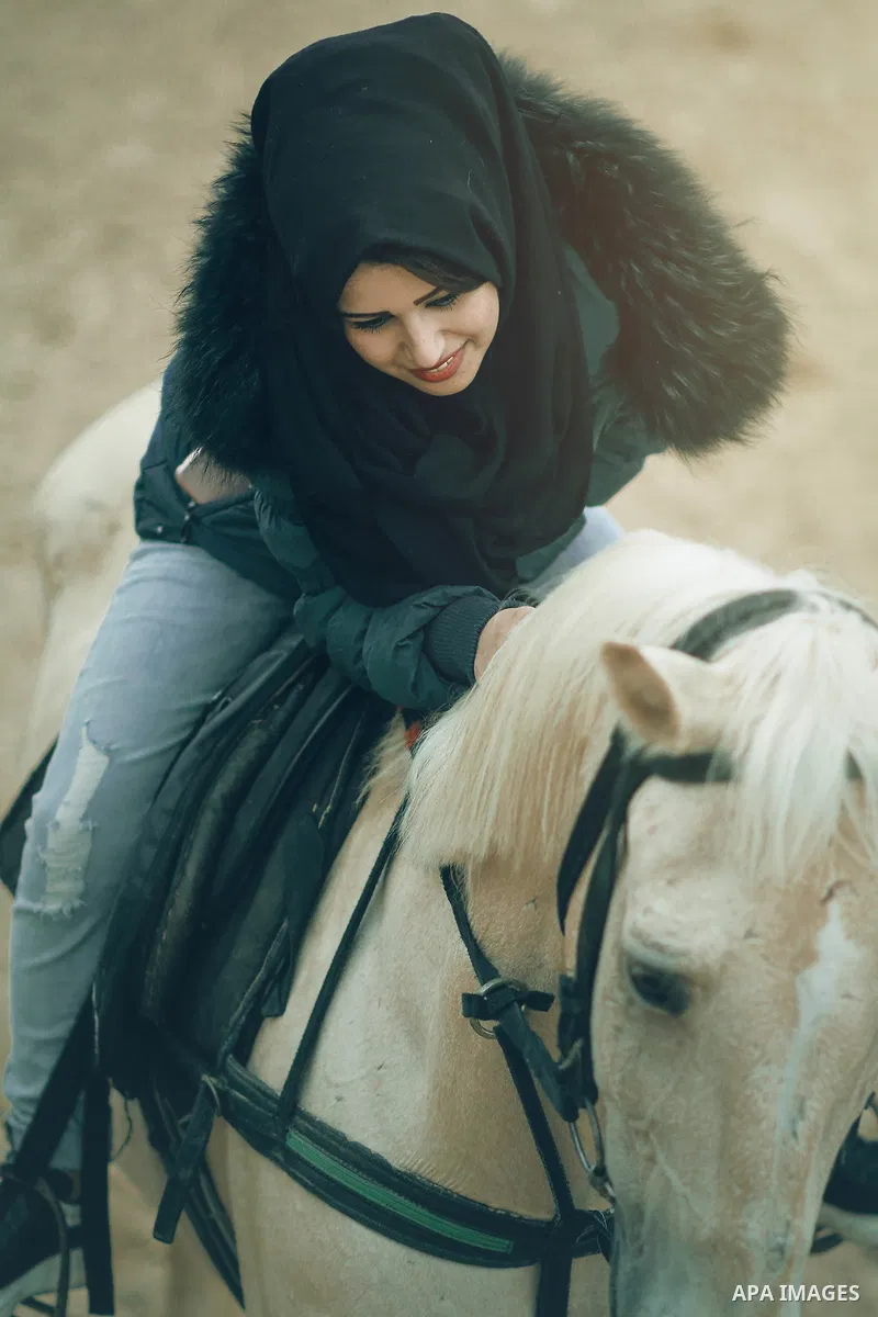 A happy woman petting a white horse. Photo by Sanad Ltefa