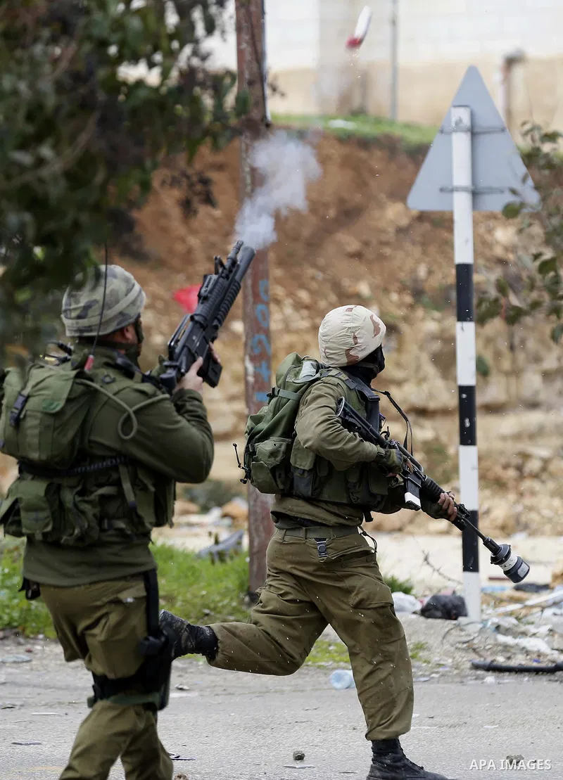 An Israeli soldier fires a teargas canister during clashes with Palestinian protestors following the funeral of Hamza Zamareh in Halhoul, in the West Bank city of Hebron on February 17, 2018. Hamza stabbed a security gua...