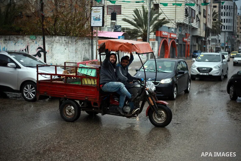 Palestinian school children walk in a flooded street during heavy rain in Gaza City on February 18, 2018. Photo by Mahmoud Ajour