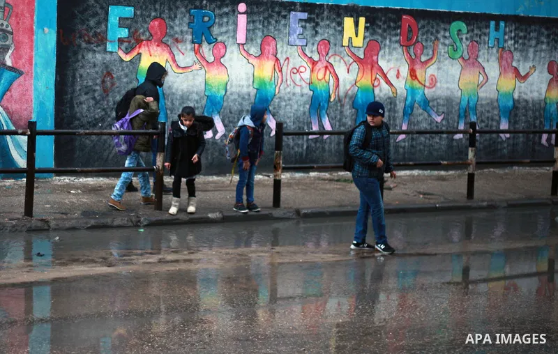 Palestinian school children walk in a flooded street during heavy rain in Gaza City on February 18, 2018. Photo by Mahmoud Ajour
