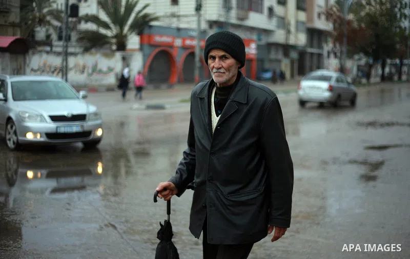 A Palestinian man walks in a flooded street during heavy rain in Gaza City on February 18, 2018. Photo by Mahmoud Ajour
