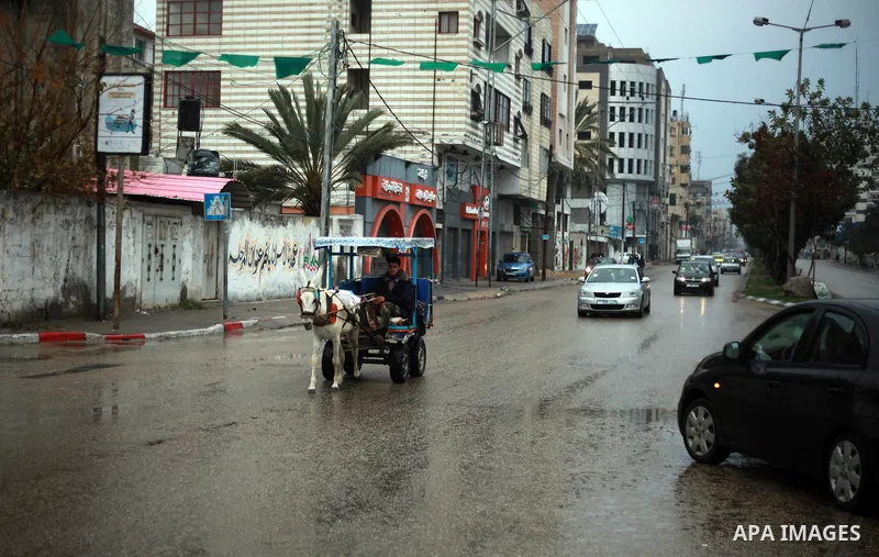 Palestinian school children walk in a flooded street during heavy rain in Gaza City on February 18, 2018. Photo by Mahmoud Ajour