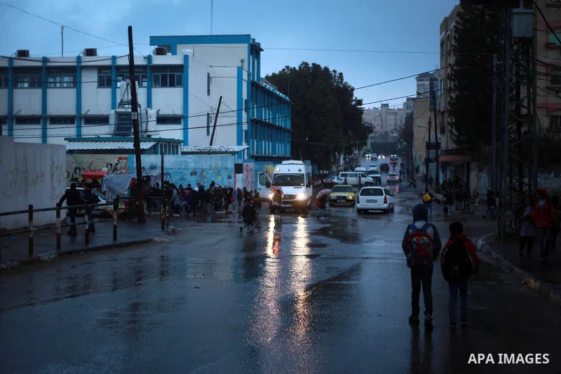 Palestinian school children walk in a flooded street during heavy rain in Gaza City on February 18, 2018. Photo by Mahmoud Ajour