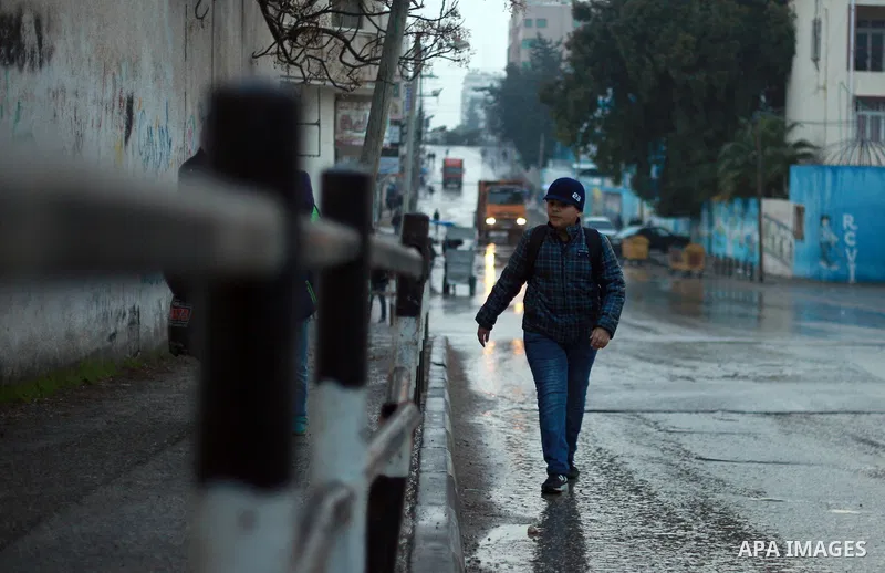 Palestinian school children walk in a flooded street during heavy rain in Gaza City on February 18, 2018. Photo by Mahmoud Ajour