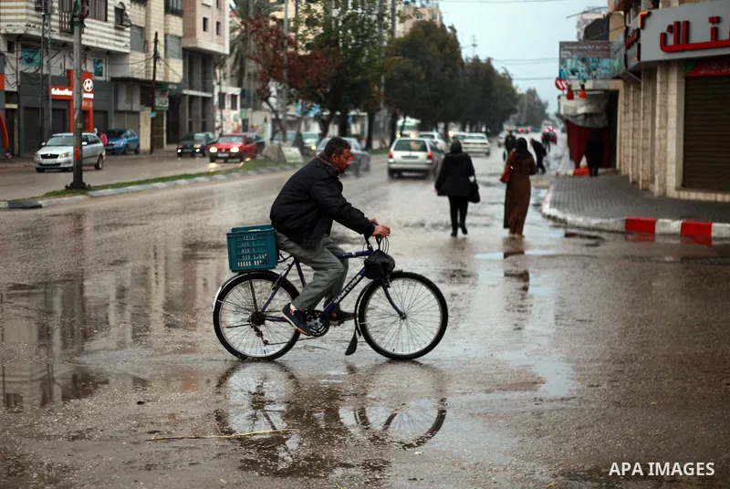 Palestinian school children walk in a flooded street during heavy rain in Gaza City on February 18, 2018. Photo by Mahmoud Ajour