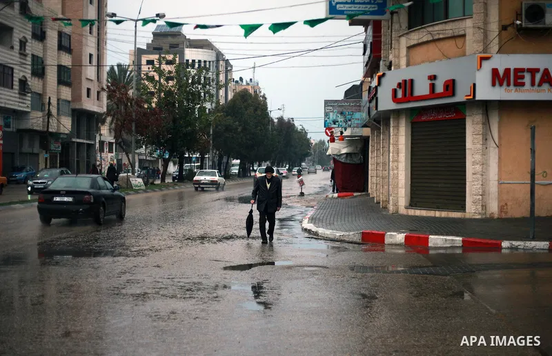 A Palestinian man walks in a flooded street during heavy rain in Gaza City on February 18, 2018. Photo by Mahmoud Ajour