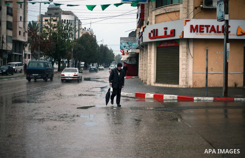 A Palestinian man walks in a flooded street during heavy rain in Gaza City on February 18, 2018. Photo by Mahmoud Ajour