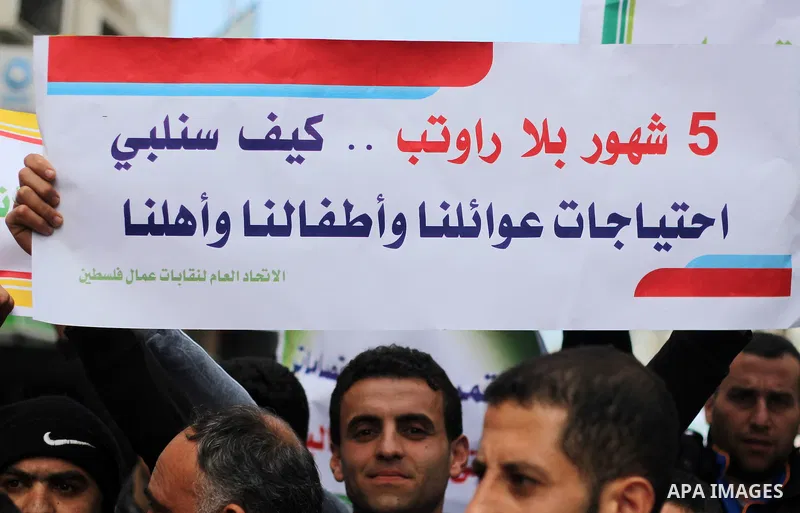 Palestinian cleaners hold banners during a protest to demand their salaries, in Gaza City on February 18, 2018. Photo by Mahmoud Ajour