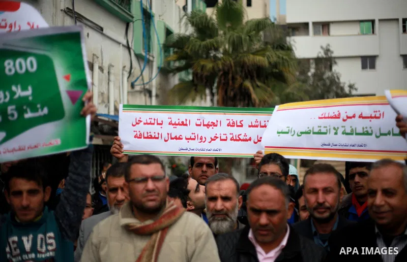 Palestinian cleaners hold banners during a protest to demand their salaries, in Gaza City on February 18, 2018. Photo by Mahmoud Ajour