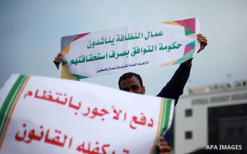 Palestinian cleaners hold banners during a protest to demand their salaries, in Gaza City on February 18, 2018. Photo by Mahmoud Ajour