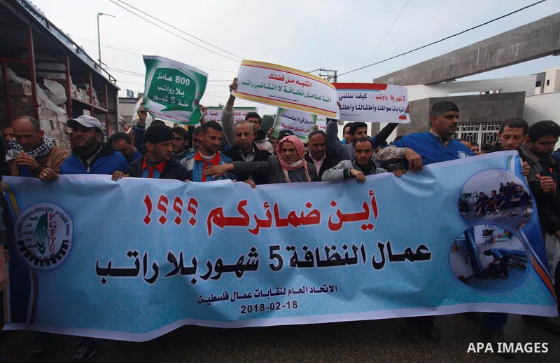 Palestinian cleaners hold banners during a protest to demand their salaries, in Gaza City on February 18, 2018. Photo by Mahmoud Ajour