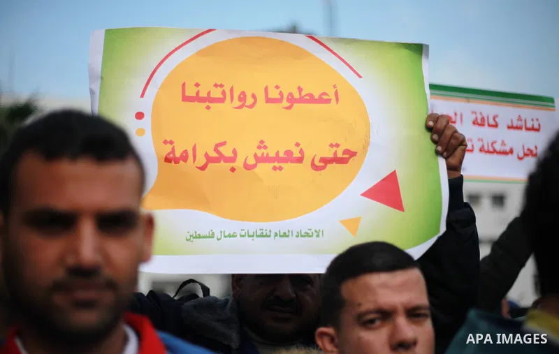 Palestinian cleaners hold banners during a protest to demand their salaries, in Gaza City on February 18, 2018. Photo by Mahmoud Ajour
