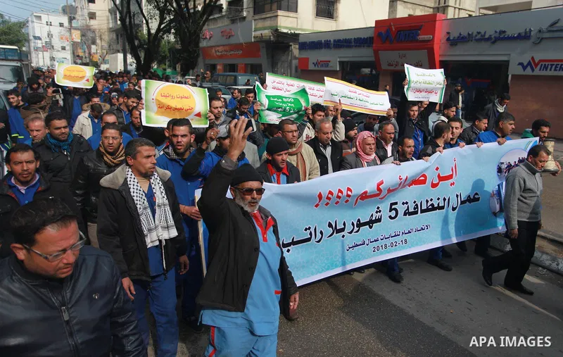 Palestinian cleaners hold banners during a protest to demand their salaries, in Gaza City on February 18, 2018. Photo by Mahmoud Ajour