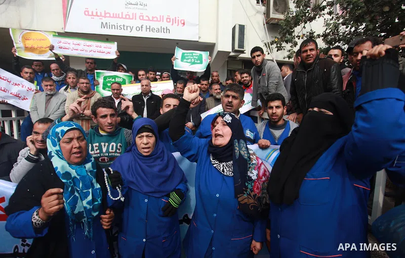 Palestinian cleaners hold banners during a protest to demand their salaries, in Gaza City on February 18, 2018. Photo by Mahmoud Ajour