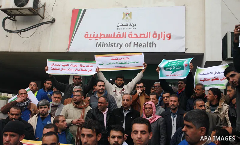 Palestinian cleaners hold banners during a protest to demand their salaries, in Gaza City on February 18, 2018. Photo by Mahmoud Ajour