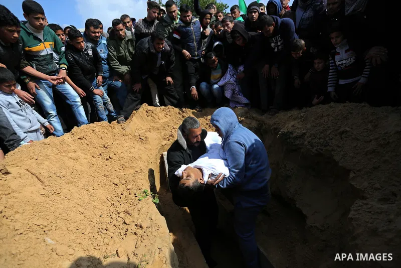 Mourners bury the body of one of two Palestinian teenagers who were killed following Israeli air strikes, during their funeral, in Rafah in the southern Gaza Strip on February 18, 2018. Two Palestinians were killed by Is...