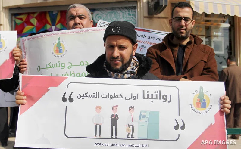 Palestinian employees of Gaza strip hold banners during a demonstration demanding their salaries in Gaza city on February 19, 2018. Photo by Mahmoud Ajour