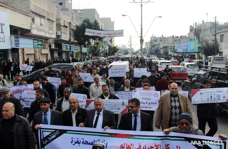 Palestinian employees of Gaza strip hold banners during a demonstration demanding their salaries in Gaza city on February 19, 2018. Photo by Mahmoud Ajour
