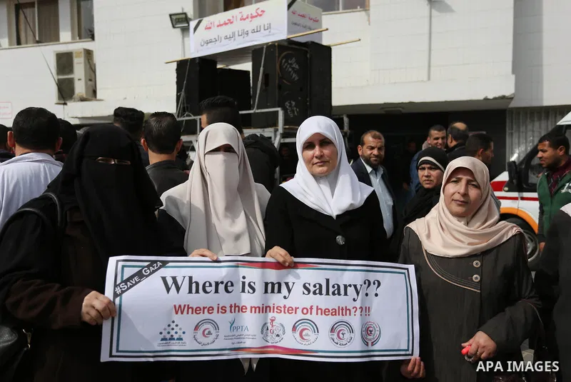 Palestinian employees of Gaza strip hold banners during a demonstration demanding their salaries in Gaza city on February 19, 2018. Photo by Ashraf Amra
