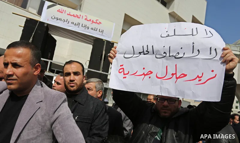 Palestinian employees of Gaza strip hold banners during a demonstration demanding their salaries in Gaza city on February 19, 2018. Photo by Ashraf Amra