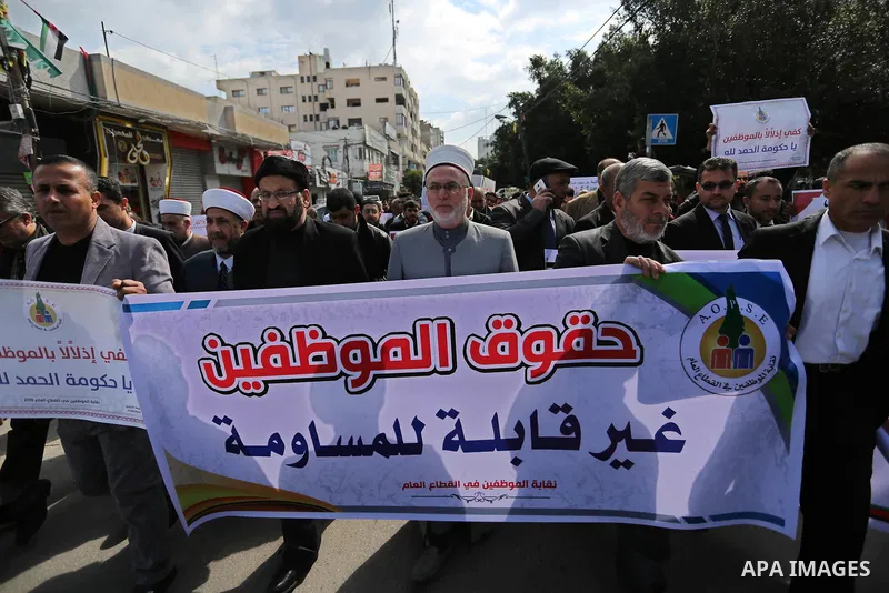 Palestinian employees of Gaza strip hold banners during a demonstration demanding their salaries in Gaza city on February 19, 2018. Photo by Ashraf Amra