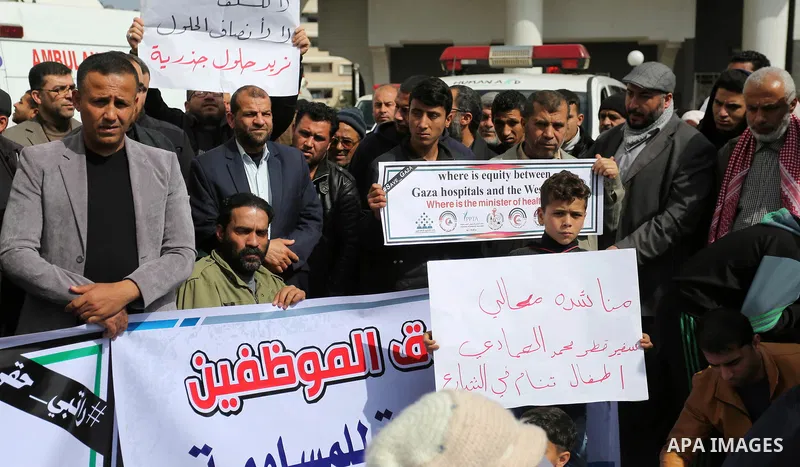 Palestinian employees of Gaza strip hold banners during a demonstration demanding their salaries in Gaza city on February 19, 2018. Photo by Ashraf Amra