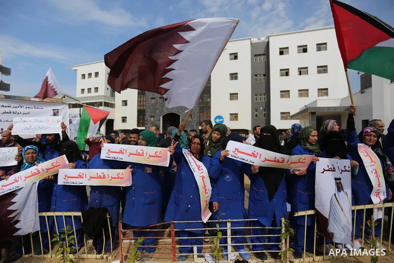 Palestinian cleaners in al-Shifa hospital hold Qatari flags and placards to demand thier salaries during a press conference of Qatar's Ambassador to the Palestinian Authority, Mohammed Al Emadi in Gaza city on February 1...