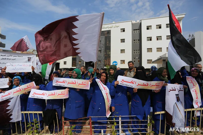 Palestinian cleaners in al-Shifa hospital hold Qatari flags and placards to demand thier salaries during a press conference of Qatar's Ambassador to the Palestinian Authority, Mohammed Al Emadi in Gaza city on February 1...